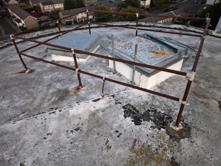 Drone roof inspection view of a flat roof with rooflights and safety railings